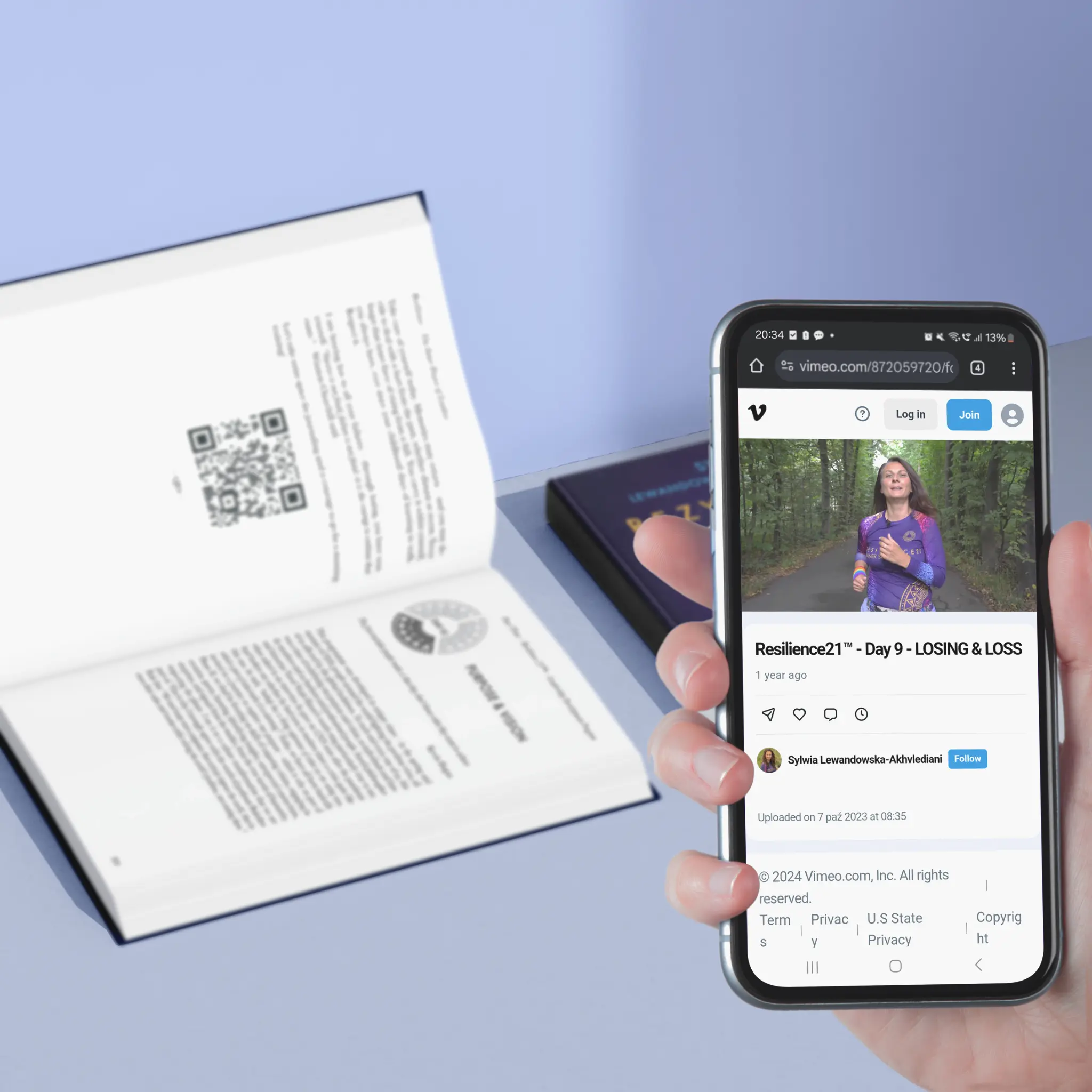 Zdjęcie pokazuje książkę oraz telefon z video po zeskanowaniu kodu QR